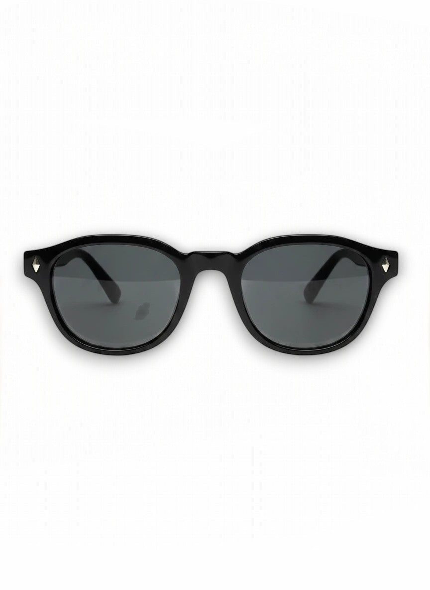 Aurélio Eyewear VI zonnebril met een zwart rond acetaat montuur en subtiele metalen accenten op de zijkanten.